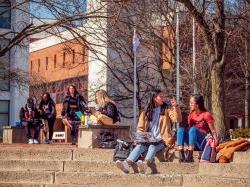 A handful of students sitting outside enjoying the day.